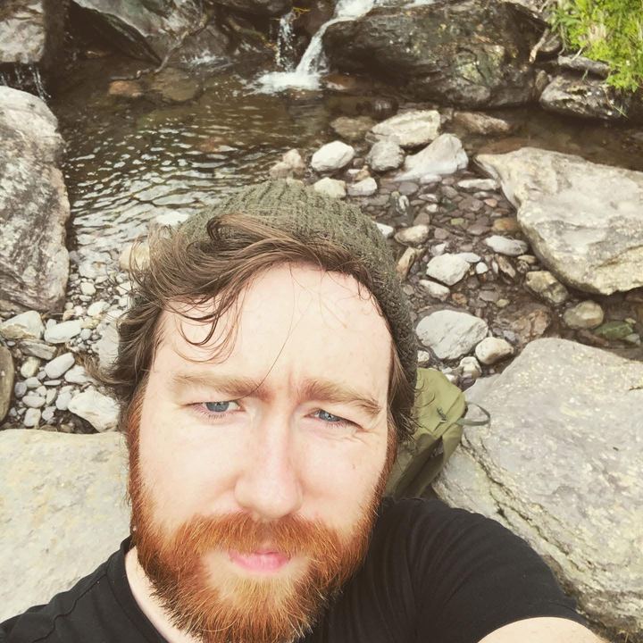 Selfie by a mountain stream, wearing a knitted hat