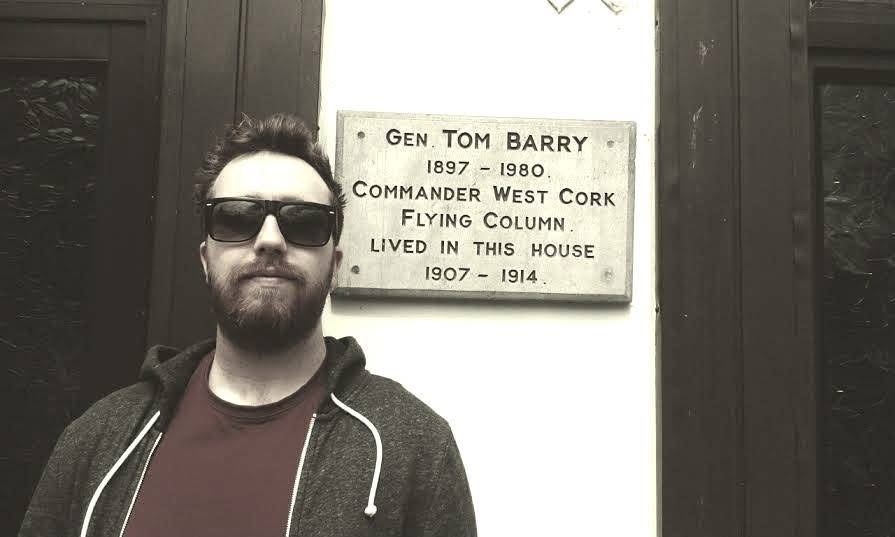 Ryan in sunglasses beside a plaque for General Tom Barry